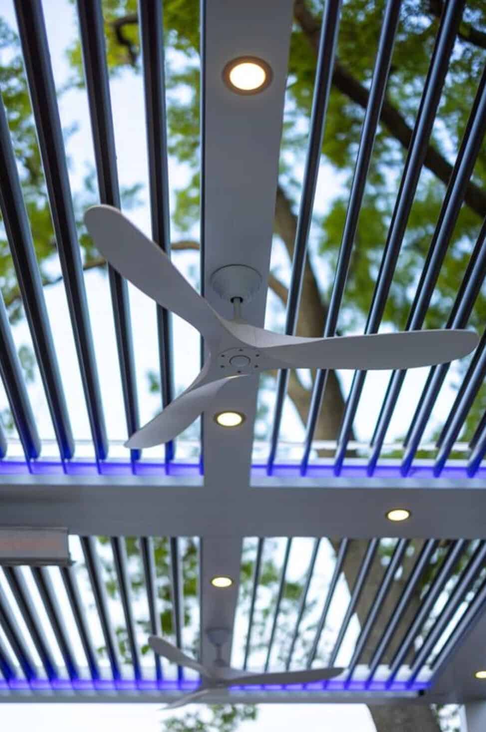 Ceiling fan with built-in lights installed on a modern outdoor pergola.