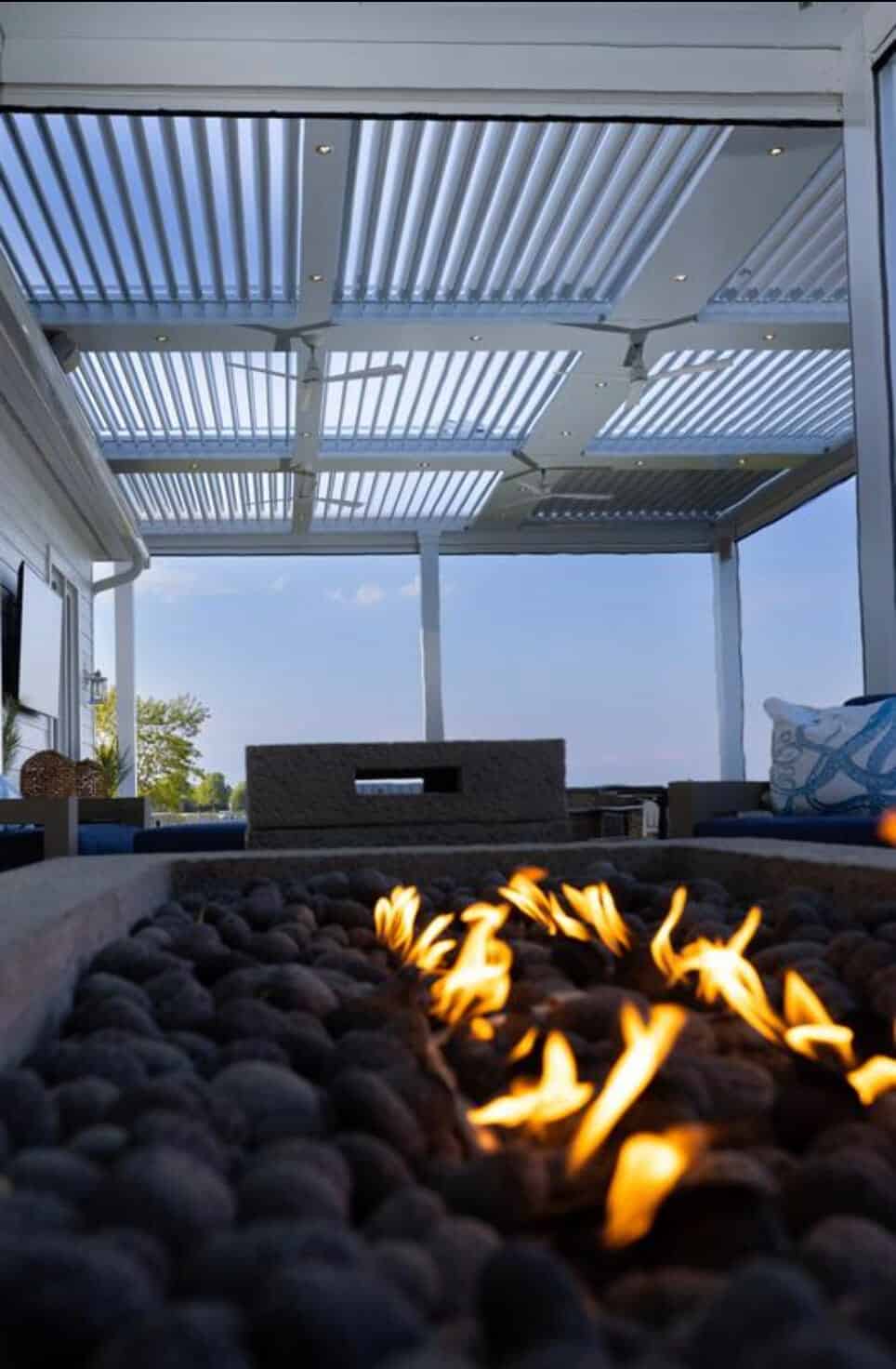 Modern outdoor patio cover with fire pit and slatted roof for shade and style.
