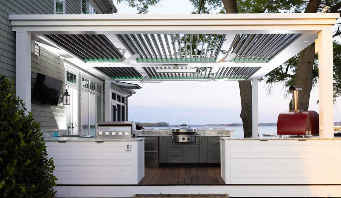 Modern outdoor kitchen with pergola and waterfront scenery for outdoor entertaining.