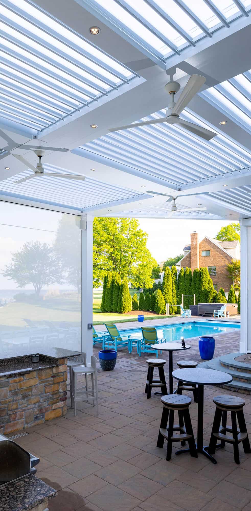 Bright screened porch with ceiling fans, skylights, and outdoor seating area.